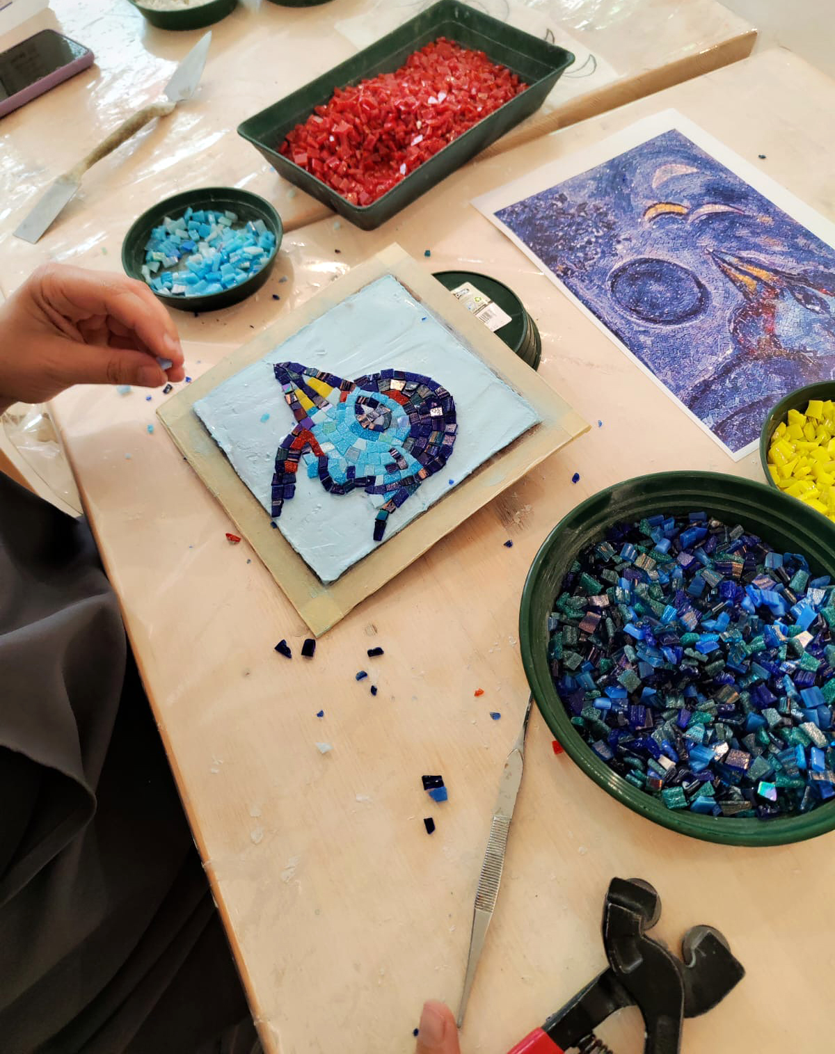 foto delle mani di una persona che realizzano un mosaico ispirato a Chagall 