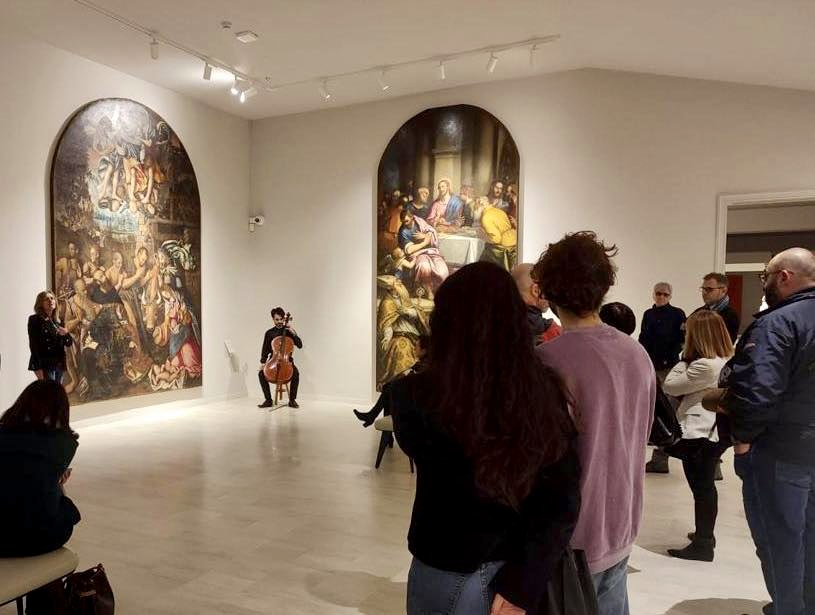 Foto di un violoncellista e di una guida museale con il pubblico.